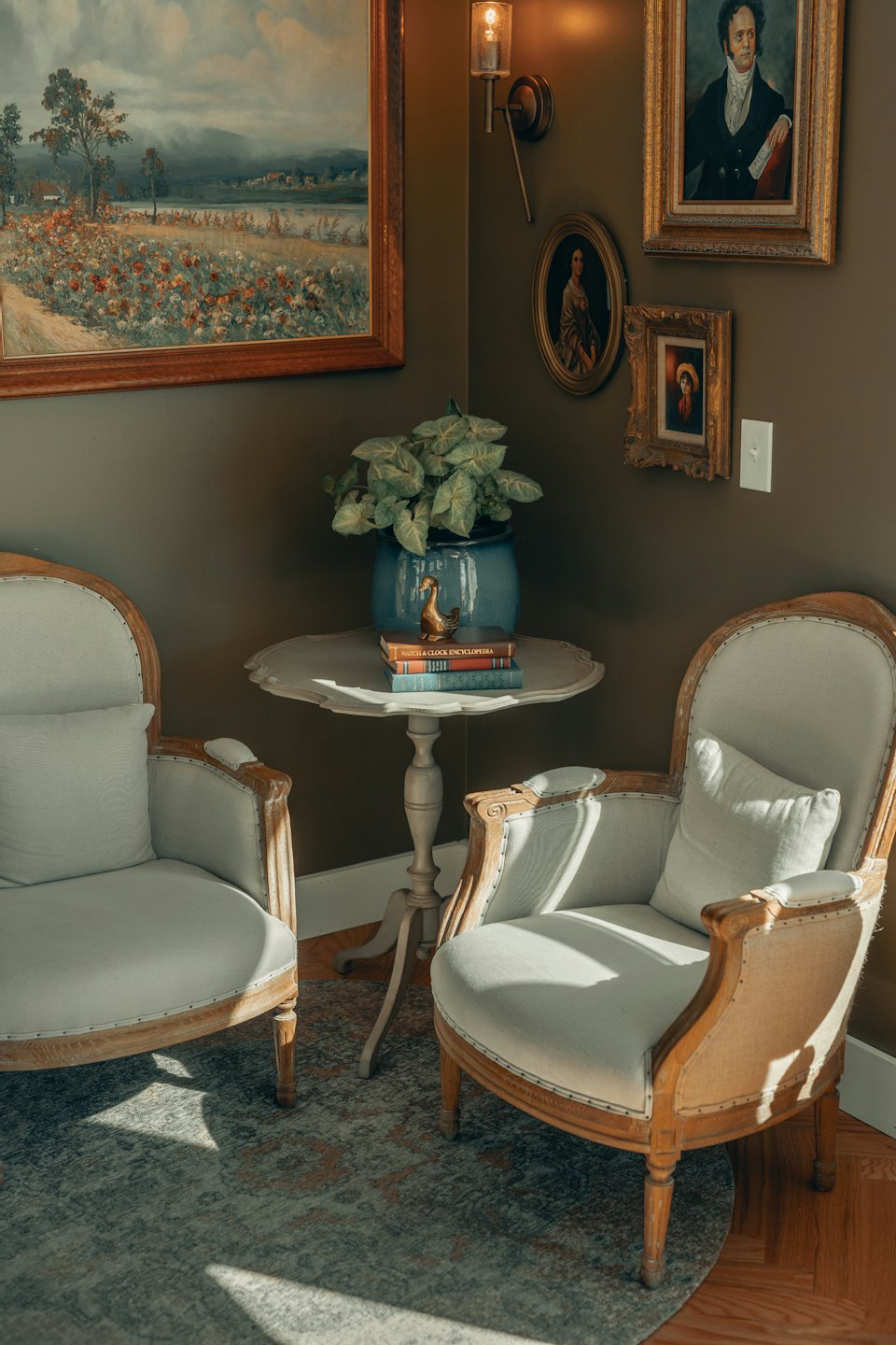 Two armchairs by a side table with a plant and books.