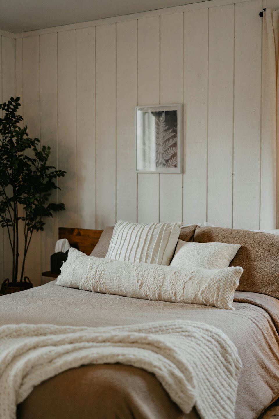Cozy bedroom with a neatly made bed and botanical art.