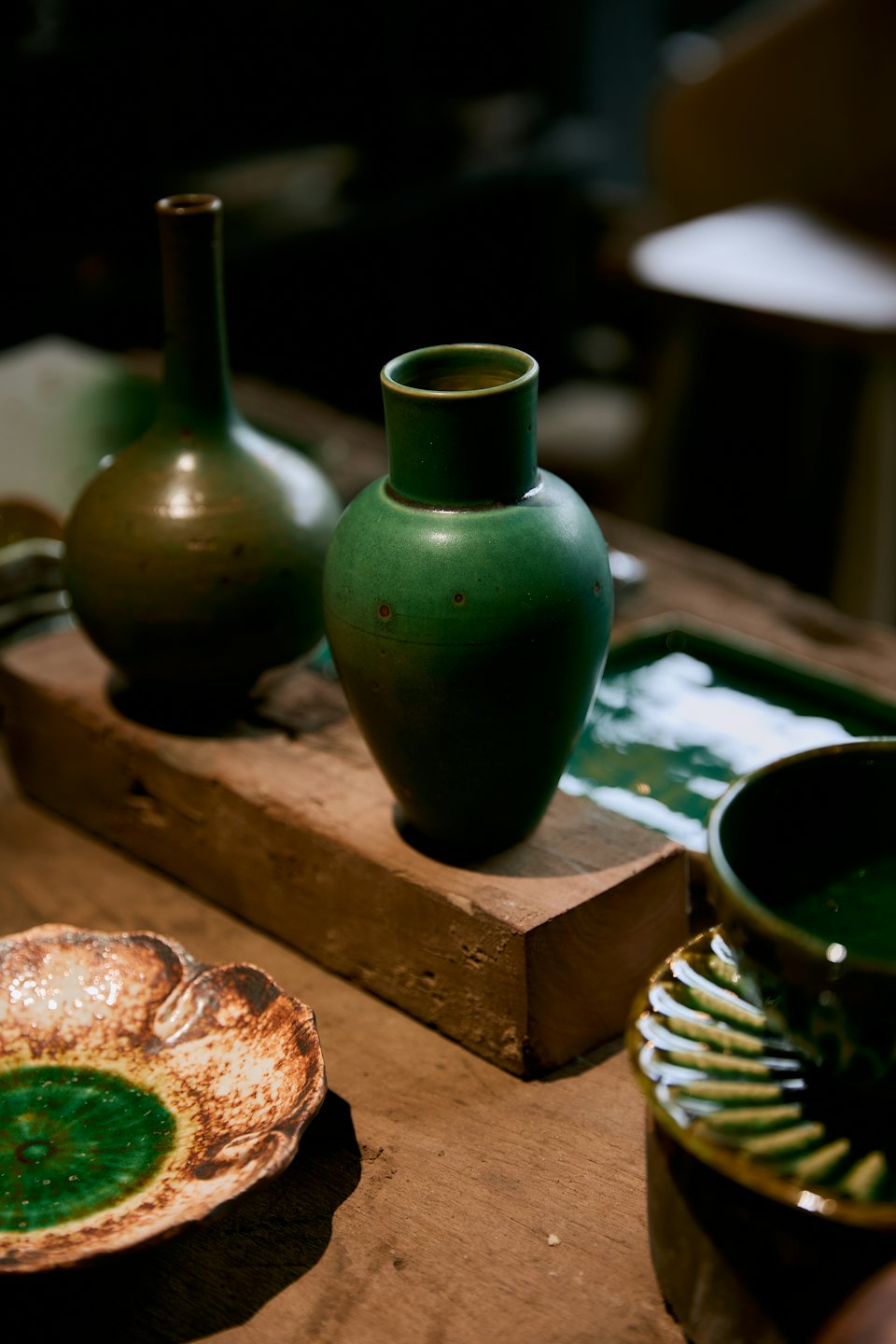 Handcrafted green ceramic pottery displayed on a wooden table.