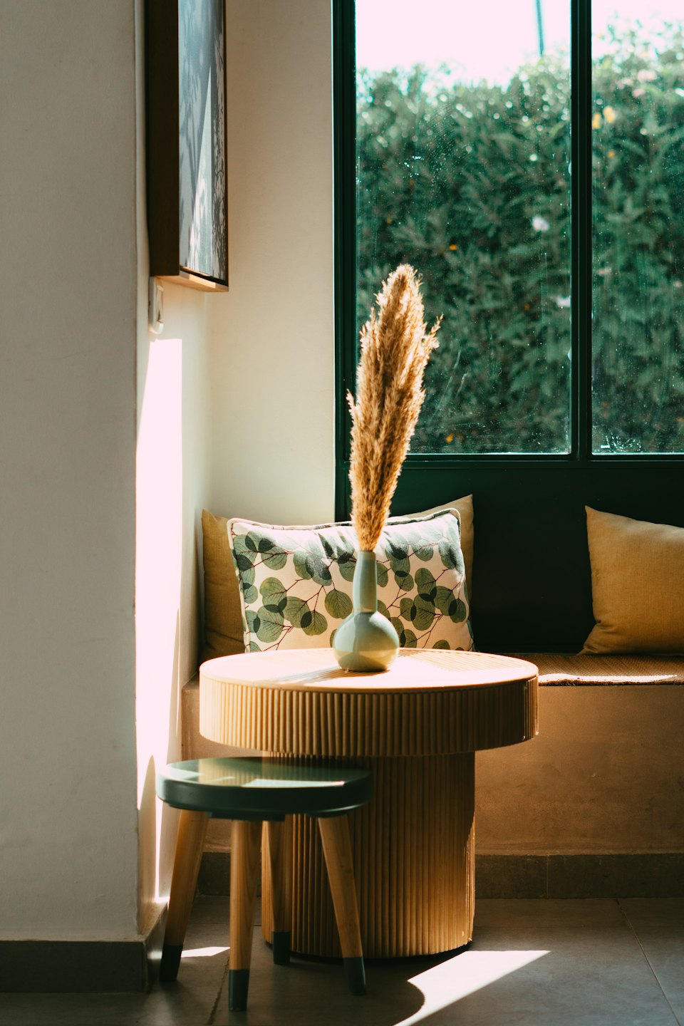 Sage green vase with pampas grass on a wooden side table.